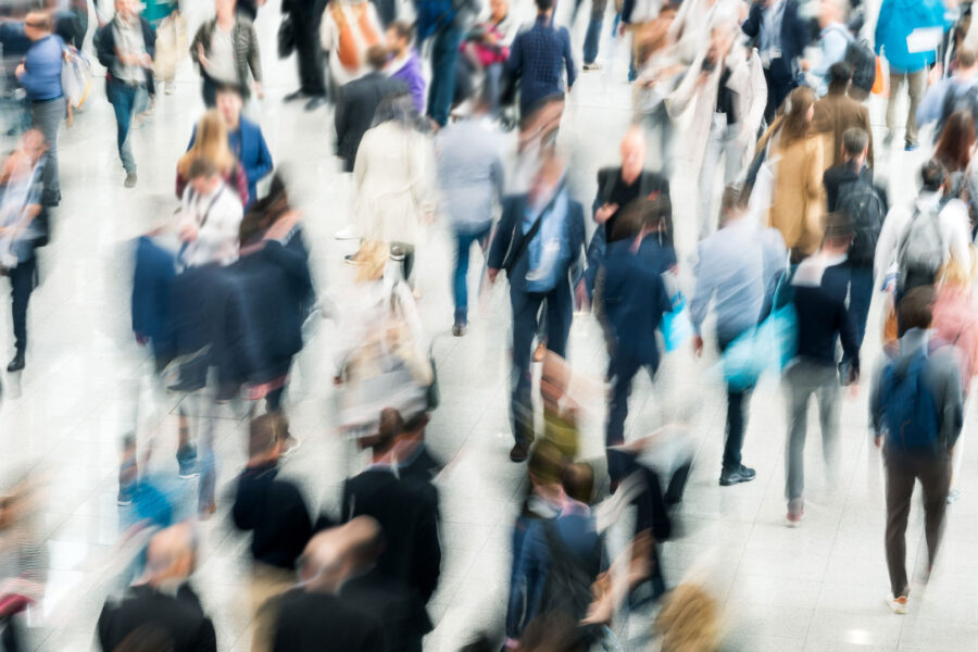 Fólk á ferð í stórum sal, myndin er óskýr (blurruð) þannig að ekki sést í andlit.