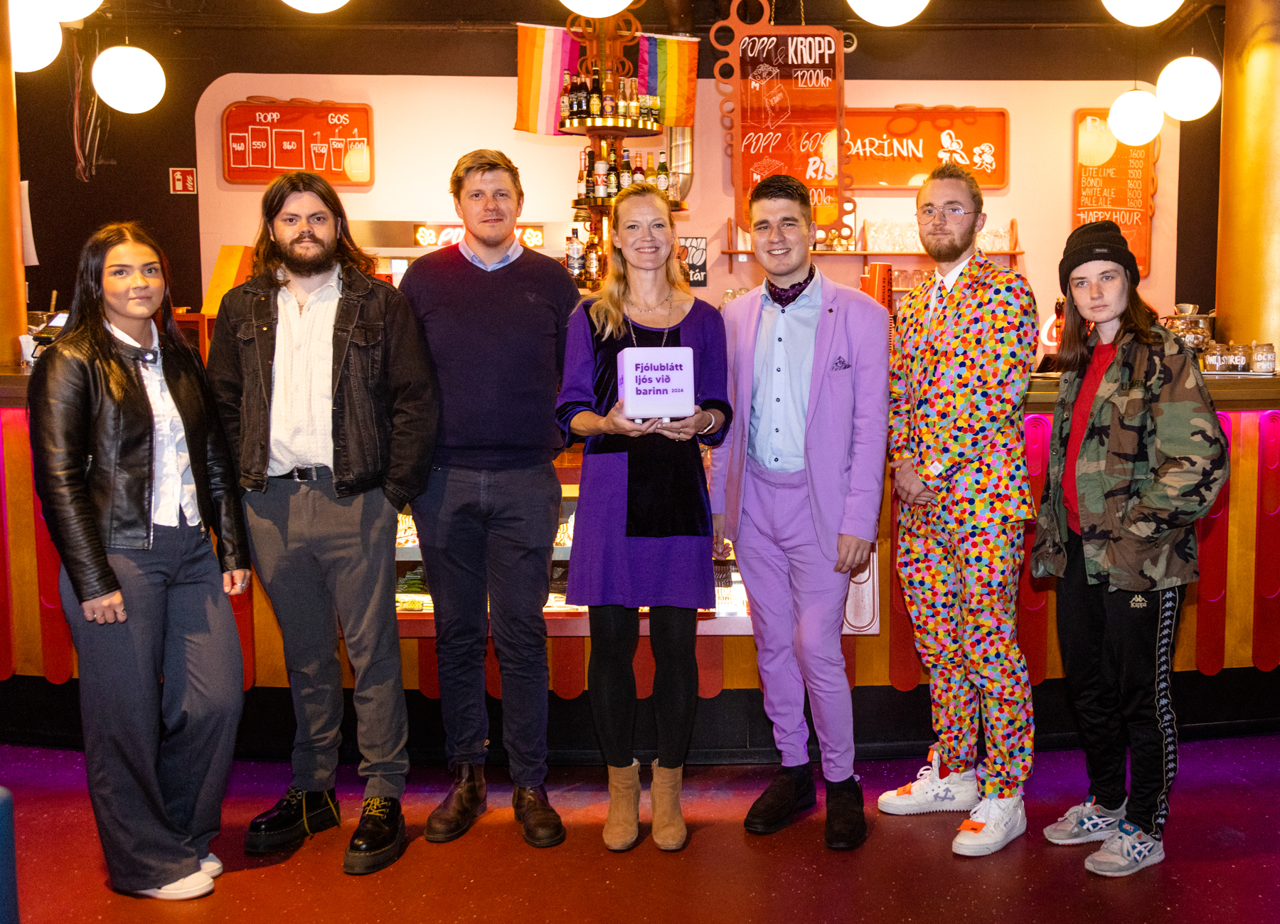 Hópmynd af fólki í Bíó Paradís. Þau standa við barinn. Í bakgrunni sést í regnbogafána.