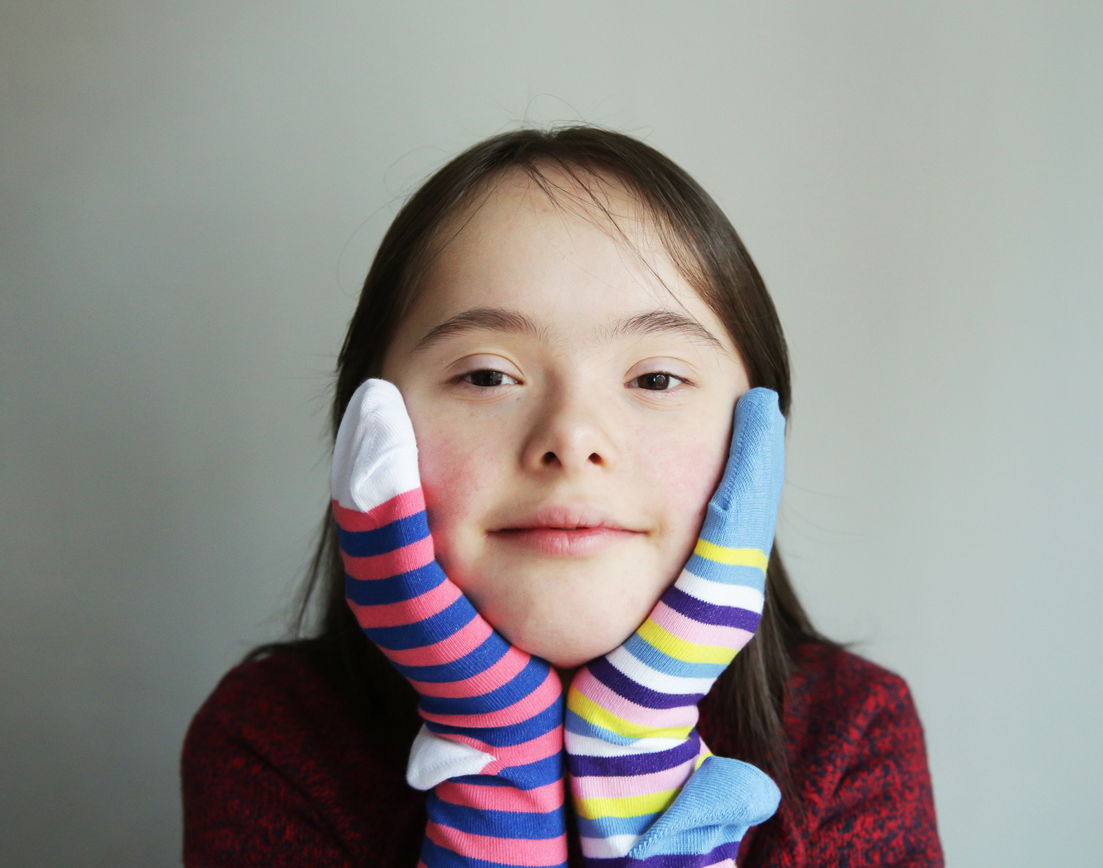 Stúlka mðe downs heilkenni með mislita sokka á báðum höndum.